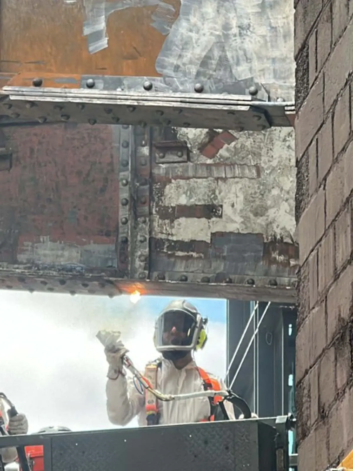 Technician using laser cleaning to remove rust and corrosion from structural steel beam under a bridge