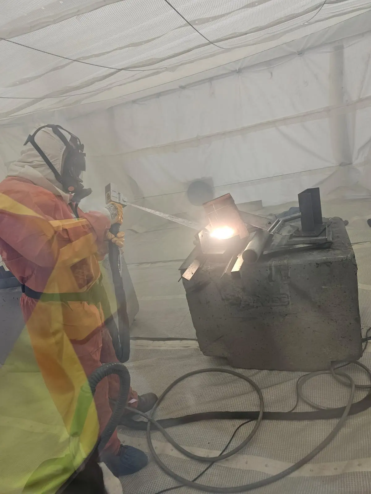 Technician performing lead paint removal using high-powered laser in a sealed containment area